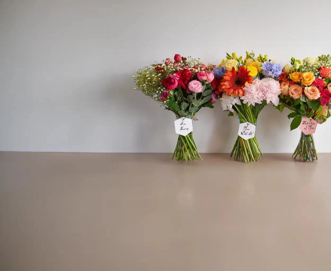 Three colorful flower bouquets on a neutral surface with a plain background