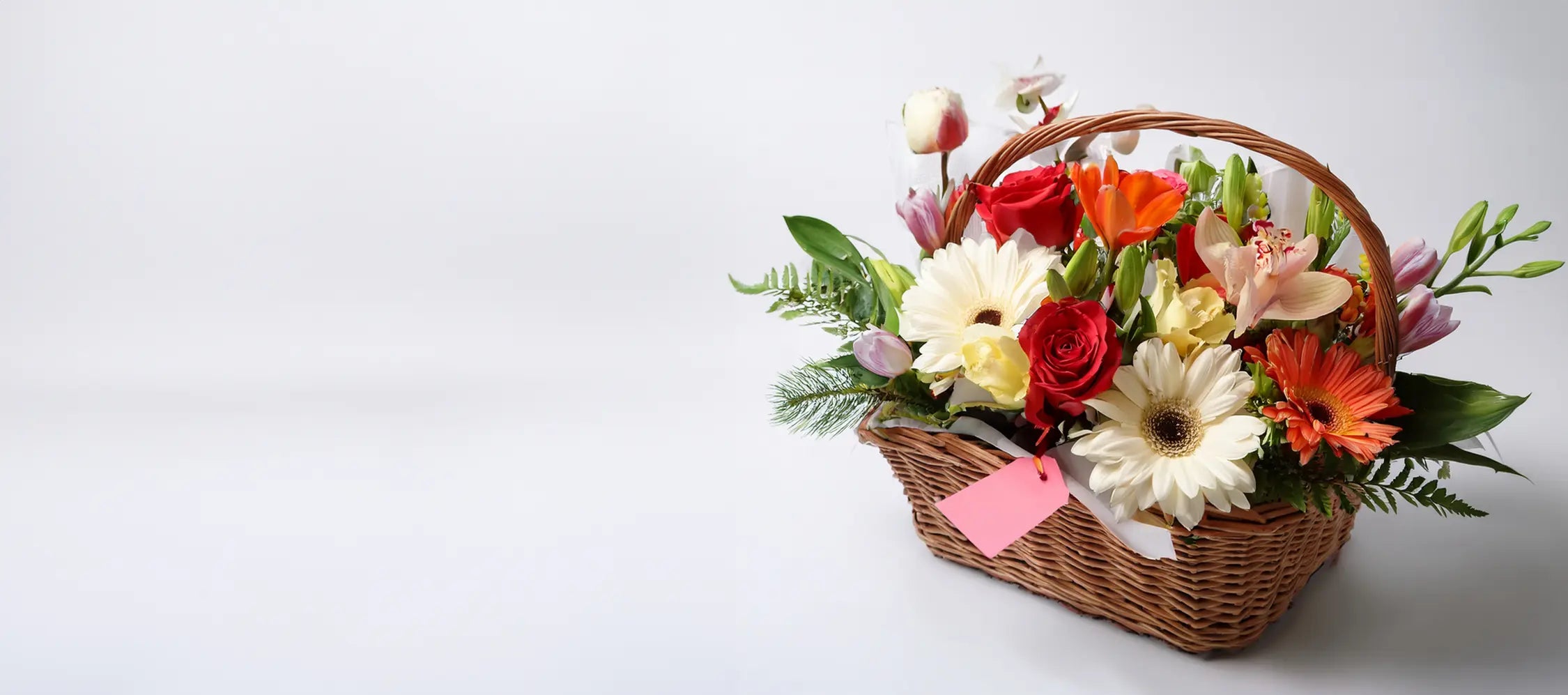 Wicker basket filled with a colorful arrangement of flowers on a white background