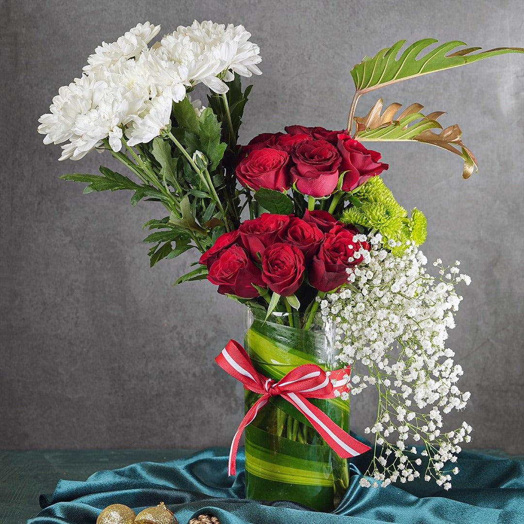 Bouquet of red roses and white flowers with a red ribbon in a green vase on a gray background. fresh flowers