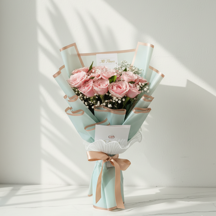Bouquet of pink roses wrapped in light blue paper with a lace ribbon on a white background. flower hampers