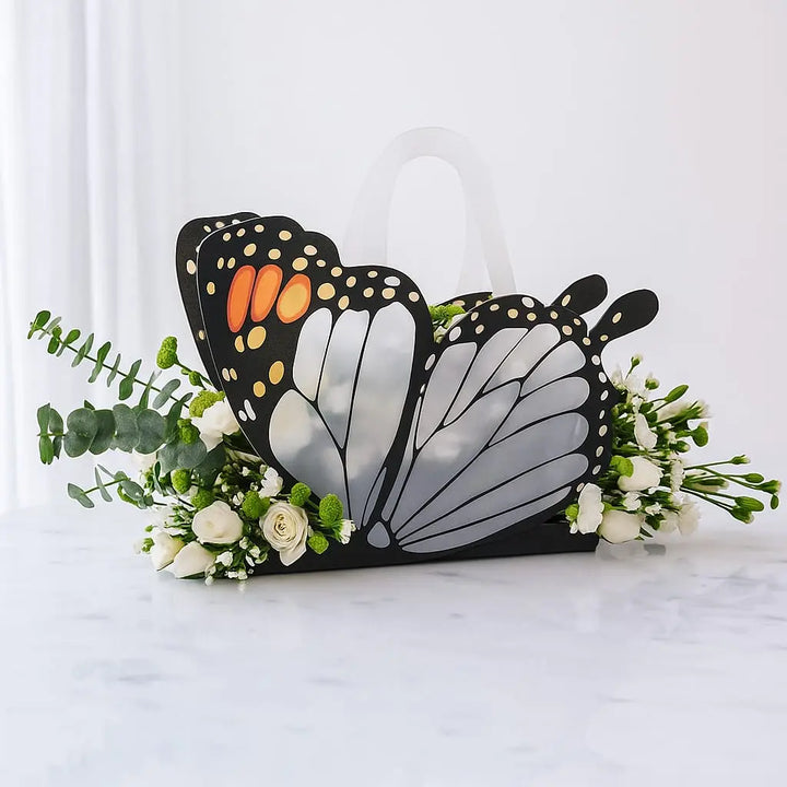 Butterfly-shaped gift bag with flowers on a white marble surface