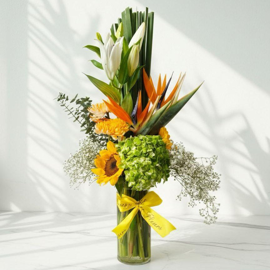 Bouquet of flowers in a clear vase with a yellow ribbon on a white background