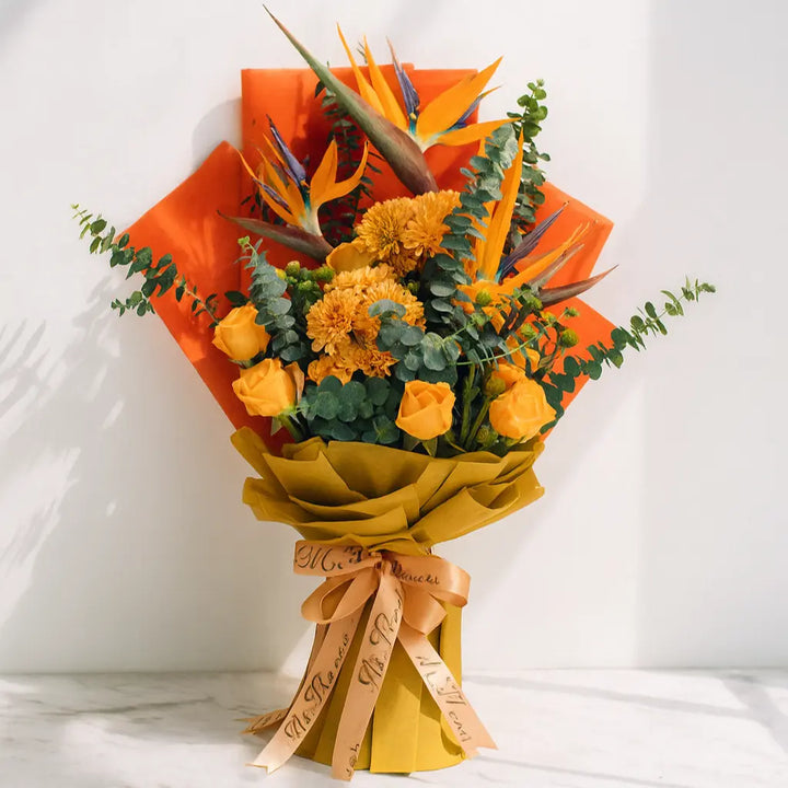 Bouquet of orange flowers with green leaves and a yellow ribbon on a white background
