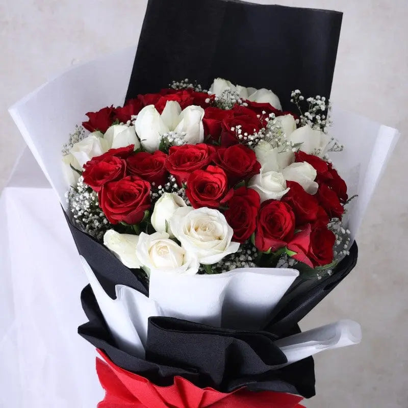 Bouquet of red and white roses wrapped in black paper.