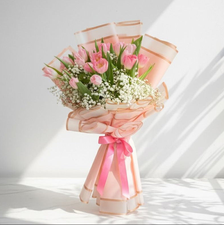 Bouquet of pink tulips with a pink ribbon on a white surface hand bouquets