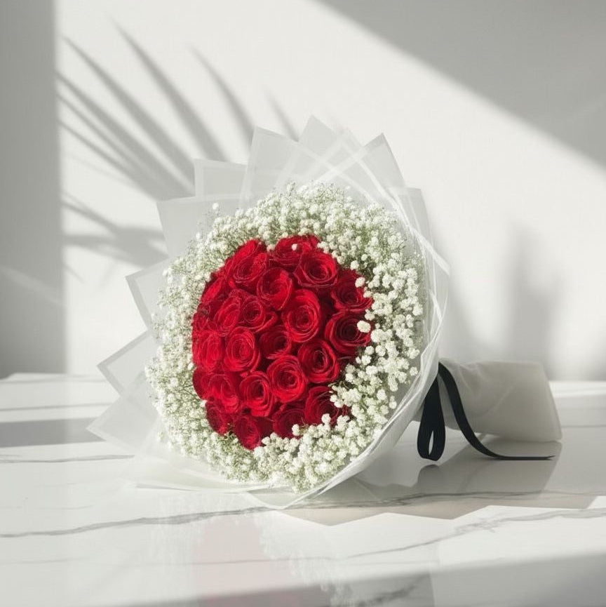 Bouquet of red roses and white flowers on a white surface with a light gray background