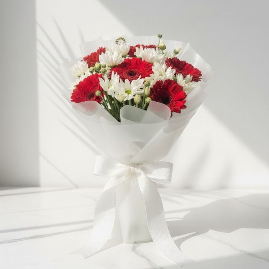 Bouquet of red and white flowers wrapped in white paper on a light gray background