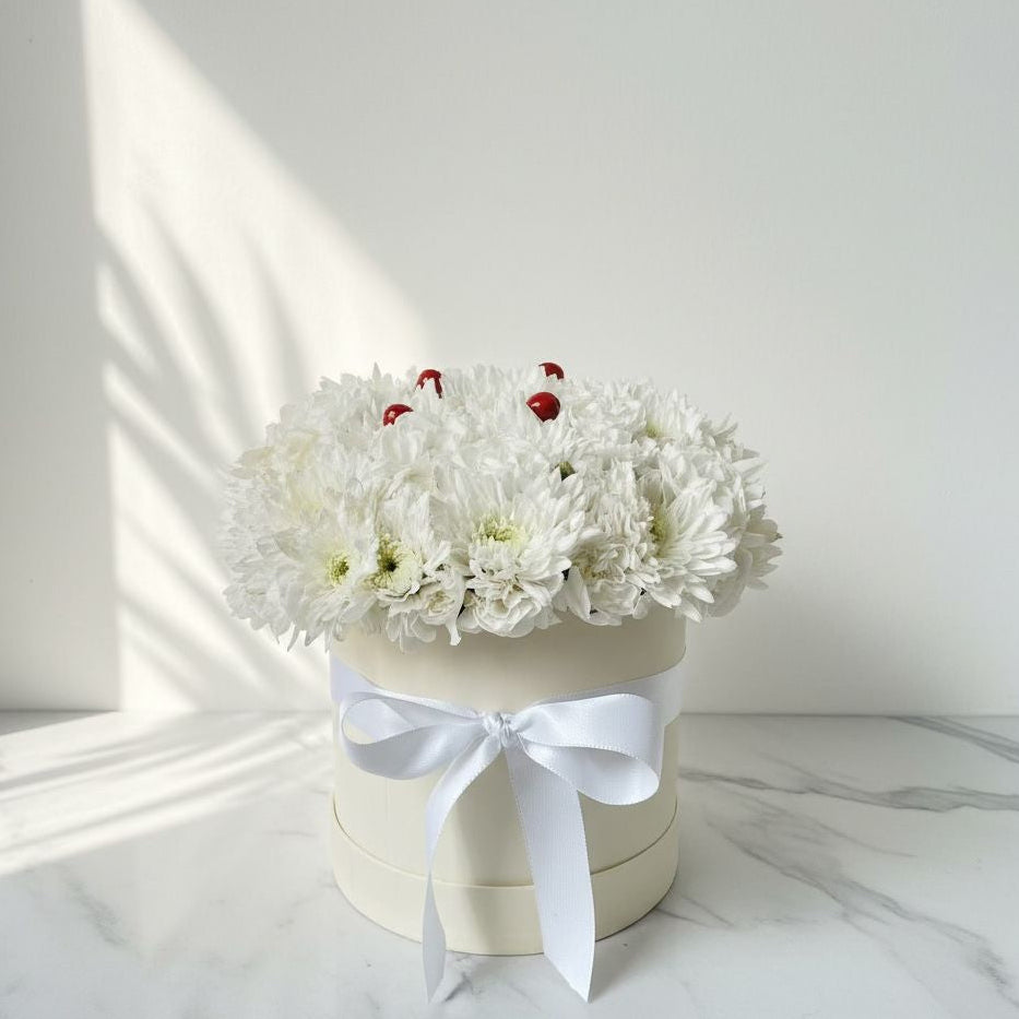 White flowers in a box with a white ribbon on a marble surface