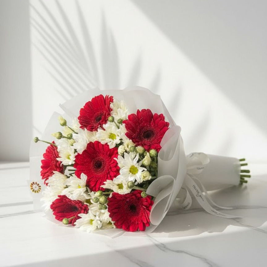Bouquet of red and white flowers on a white surface with a white background