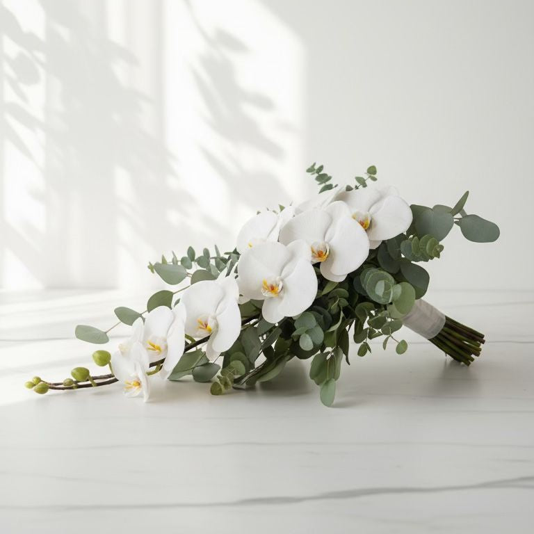 Bouquet of white orchids and greenery on a light surface with a neutral background bridal bouquet wedding 