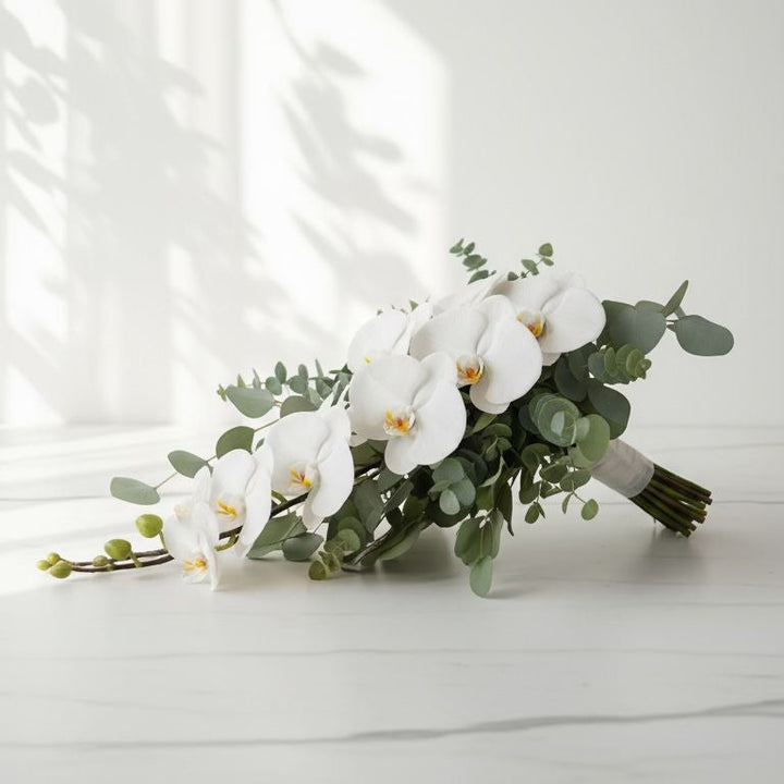 Bouquet of white orchids and greenery on a light surface with a neutral background bridal bouquet wedding 