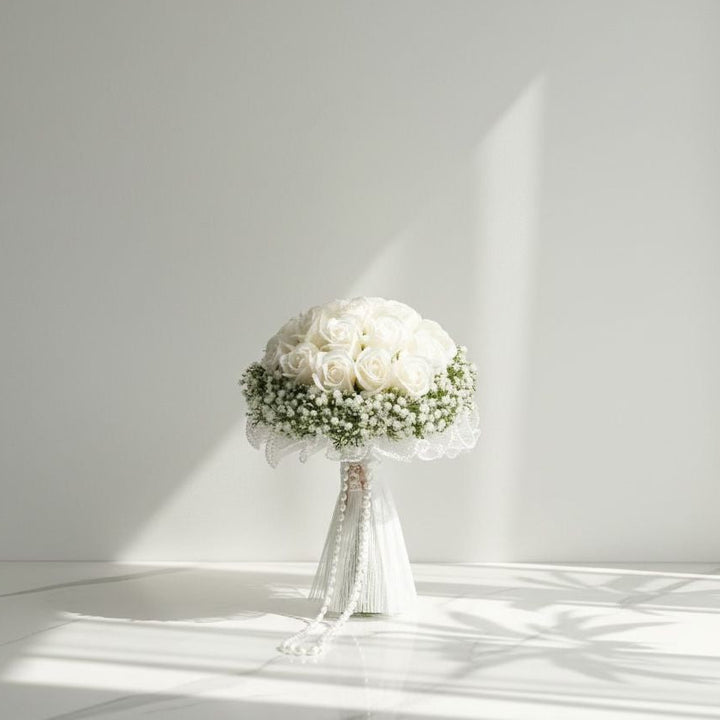 Bouquet of white flowers in a clear vase on a white surface with a light gray background bridal bouquet