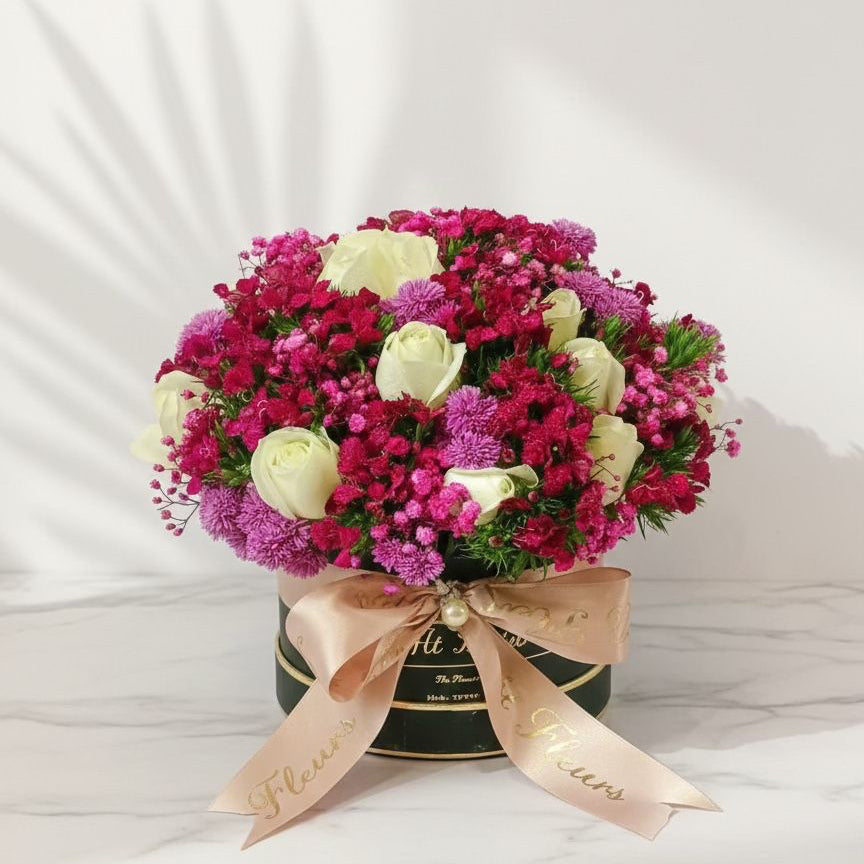 Bouquet of flowers in a box with a pink ribbon on a white background