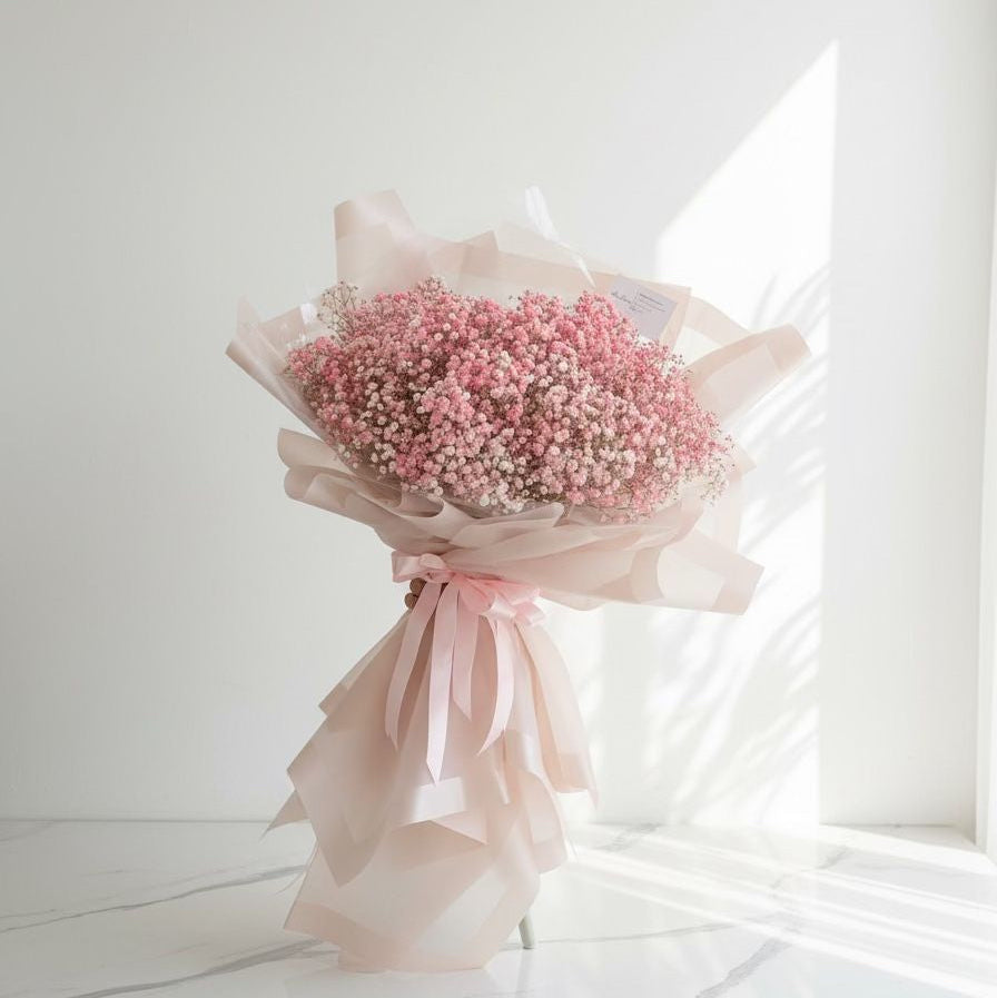 Bouquet of pink flowers with a white ribbon on a light background hand bouquet