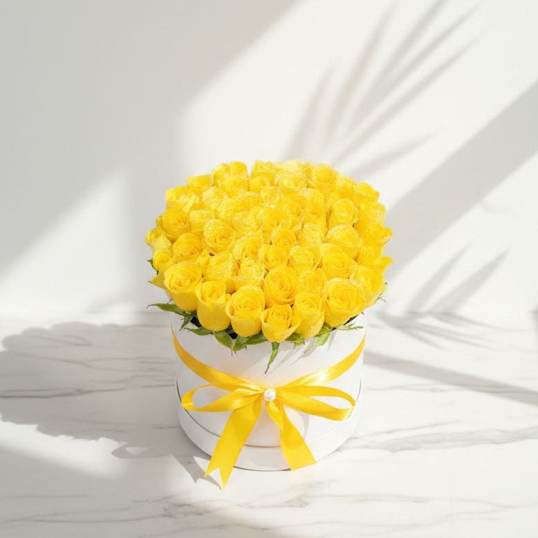 Bouquet of yellow roses in a white box with a yellow ribbon on a light background