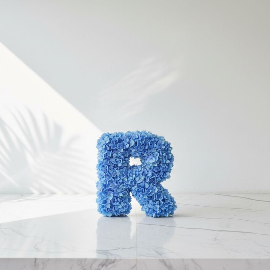 Blue letter 'R' decorative item on a marble surface with a white background