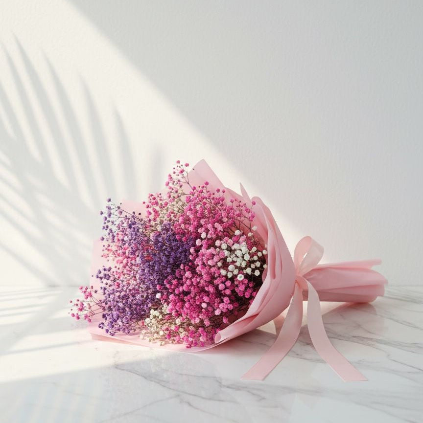 Bouquet of pink and purple flowers with a pink ribbon on a white background