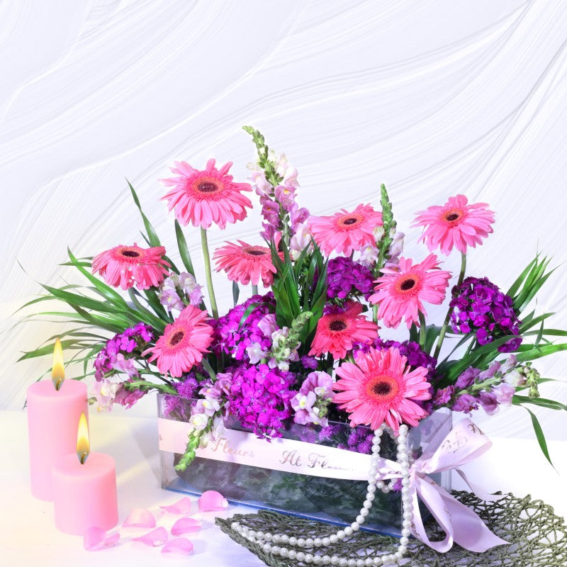 Bouquet of pink and purple flowers with candles and a pearl necklace on a white background